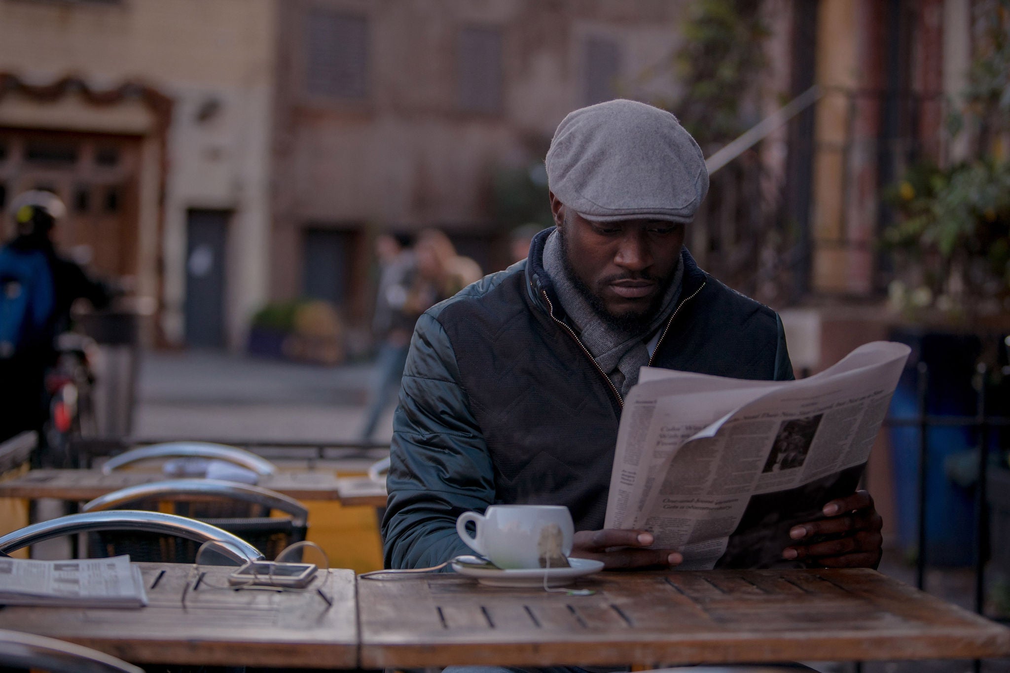 Causal man reading a newspaper at an outdoor coffee shop